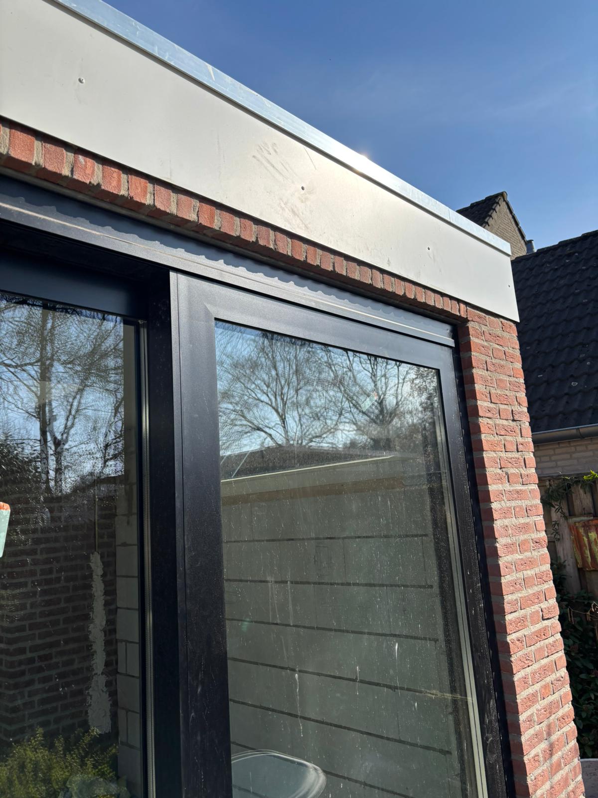 Donker aluminium kozijn in een moderne bakstenen gevel